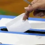 voter putting paper ballot