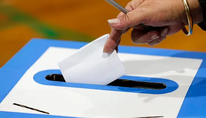 voter putting paper ballot